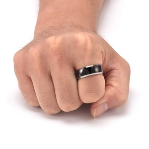 Polished black tungsten ring with silver edges worn on a clenched fist for men