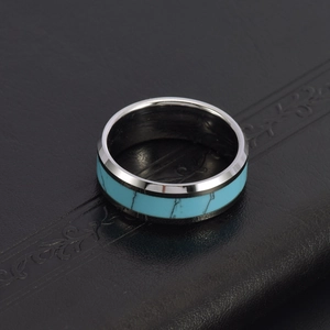 Polished tungsten ring featuring an inlaid turquoise band on a vintage leather surface
