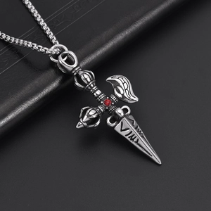 Vintage stainless steel vajra pestle pendant with red gem on black leather background