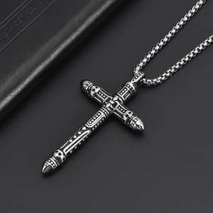 Gothic stainless steel cross necklace with skull details on a matte black stand