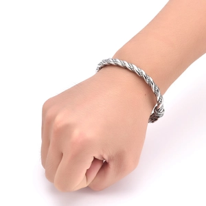 Detail of vintage Nordic viking dragon cuff bangle showing twisted metal craft on male wrist