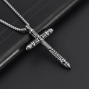 Detailed close-up of gothic stainless steel cross and sword pendant with skull carving