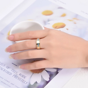 Vue détaillée d'une bague dorée en acier inoxydable avec motifs libellule bleus au doigt