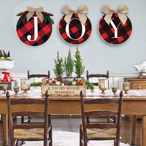 Detail of JOY buffalo plaid round wooden wall hangings with burlap bows and pine needles