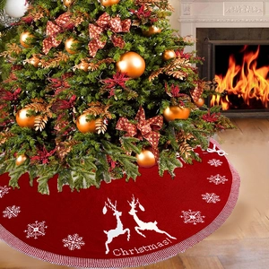 Red knitted Christmas tree skirt featuring white elk and snowflakes by a warm fireplace