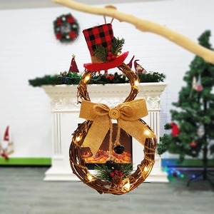 Close-up of LED snowman rattan wreath with pine needles and red berries on fireplace