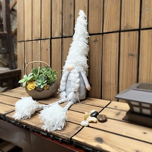 Nordic Christmas gnome plush with long legs and white braids in a cozy outdoor setting