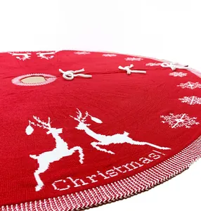 Detail of red knitted Christmas tree skirt with white reindeer and snowflake patterns