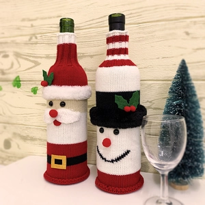 Detail of knitted Santa and Snowman wine bottle covers on a festive Christmas dining table