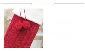 Detail of red knitted Christmas stocking with white faux fur trim and pom-pom accents