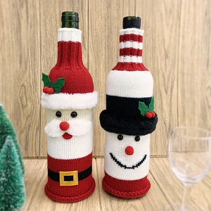 Detail of knitted Santa and snowman wine bottle covers on a wooden dining table