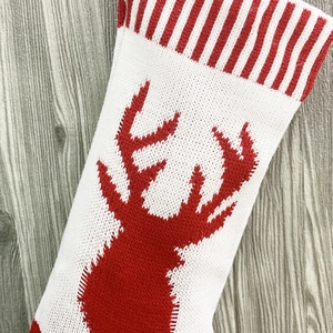 Detail of knitted Christmas stocking showing red reindeer pattern and striped cuff texture