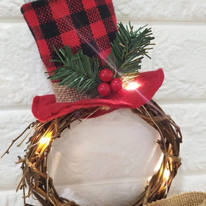 Detail of Christmas wreath with LED lights, red berries, and black plaid mini hat