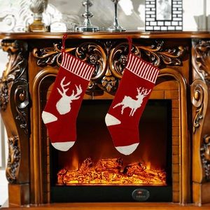 Close-up of red and white knitted Christmas stockings with reindeer patterns on fireplace