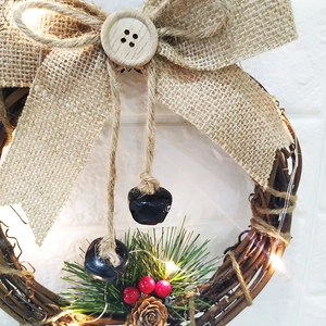 Detail of LED Christmas wreath with rustic pine cones and berries on rattan base
