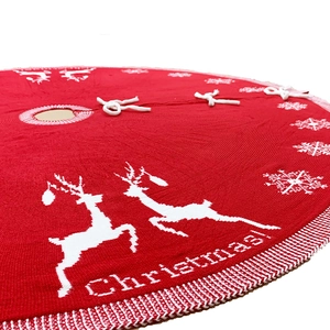 Red and white knitted Christmas tree skirt with reindeer snowflake patterns and ties