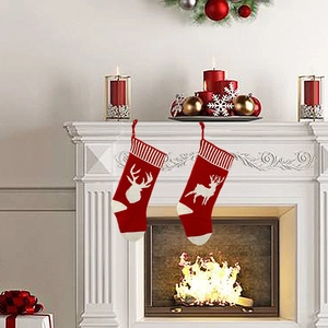 Detail view of red knitted Christmas stockings with white reindeer patterns on a fireplace