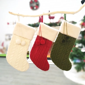 Three-piece knitted Christmas stockings with plush trim and pom-poms on white branches
