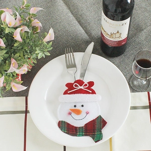 Snowman Christmas cutlery holder set with red hat and plaid scarf on white dinner plate