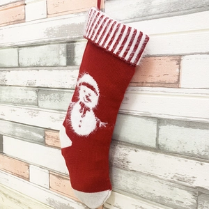 Détail d'une chaussette de Noël en tricot rouge avec motif bonhomme de neige blanc rayé