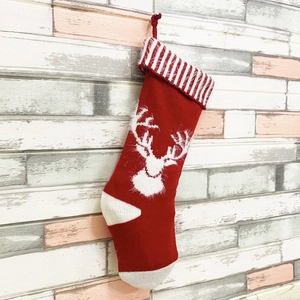 Détail de chaussette de Noël rouge en tricot avec silhouette de renne et bordure rayée