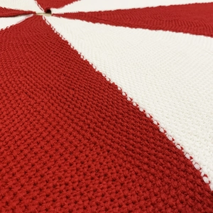 Close-up of red and white knitted Christmas tree skirt with detailed crochet texture