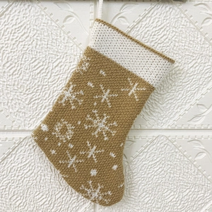 Close-up of mustard yellow knitted Christmas stocking with white snowflake pattern detail