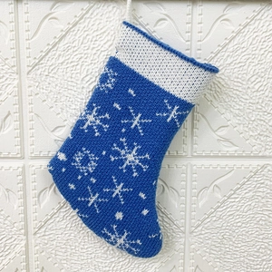 Detail of blue knitted Christmas stocking with white snowflake patterns and hanging rope