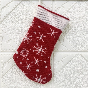 Close-up of red knitted Christmas stocking with white snowflake patterns and cream cuff