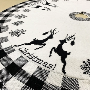 Detail of knitted Christmas tree skirt with reindeer pattern and black white plaid edge