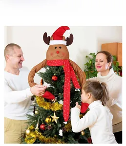 Brown plush Christmas reindeer tree topper with red hat and snowflake scarf in home setting
