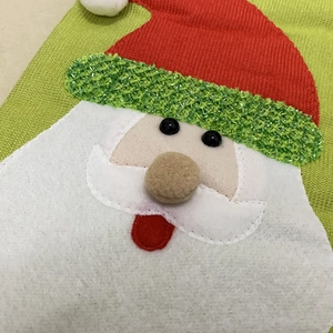 Detailed view of handmade Santa Claus felt applique on a green fabric Christmas stocking