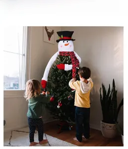 Christmas snowman tree topper with plaid scarf and black top hat on a decorated tree