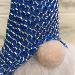 Close-up of blue knit Christmas gnome hat with silver sequins and plush round nose