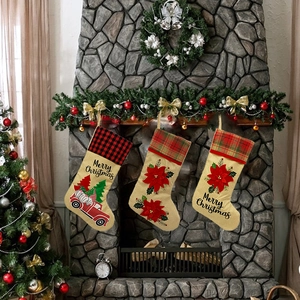 Détail de trois chaussettes de Noël en jute avec motifs festifs devant une cheminée