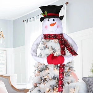 Detail of plush snowman tree topper with long plaid scarf and carrot nose on white tree
