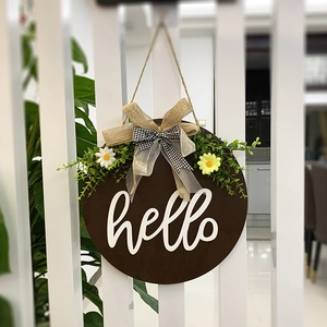 Round wooden 'hello' door sign with burlap bow, greenery and daisies for home decor
