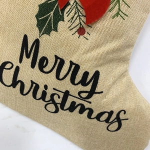 Détail d'une chaussette de Noël en lin avec texte Merry Christmas et baies décoratives
