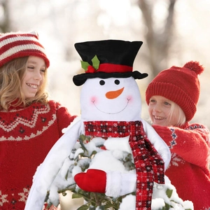 Charming snowman Christmas tree topper held by children in a cozy winter snow scene