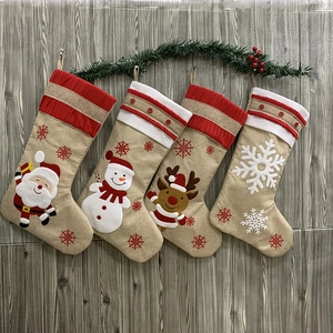 Detail von vier rustikalen Jutesocken mit Weihnachtsmann, Schneemann, Hirsch und Schneeflocke