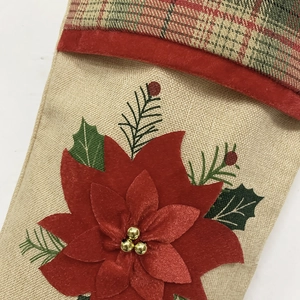 Détail de chaussette de Noël en toile de jute avec poinsettia 3D et broderie festive