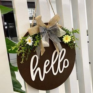 Detail of hello wooden door sign with burlap bow, green leaves and daisy flowers