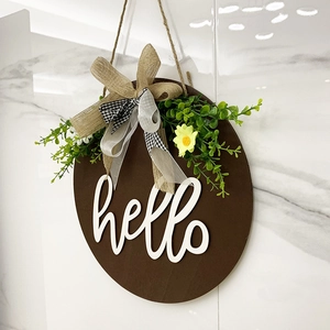 Brown wooden round welcome sign with white hello text, burlap bow and daisies