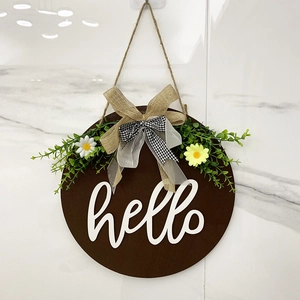 Detail of wooden welcome sign with hello letters, faux greenery, and layered bows