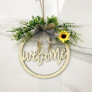 Detail of wooden welcome sign with sunflower, green plants and buffalo plaid bow decoration