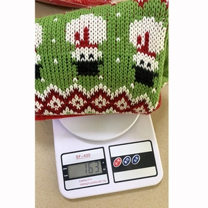 Chaussette de Noël tricotée verte pesant 163g sur une balance électronique photo