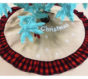 Detail of burlap Christmas tree skirt with buffalo plaid ruffle edge and snowflake print