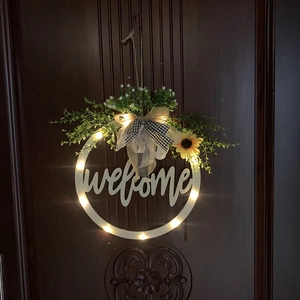 Close-up of lighted welcome door sign with sunflower, bow, and warm LED lights