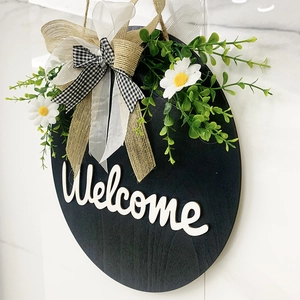 Close-up of rustic wooden welcome sign with 3D letters, greenery, and burlap bow