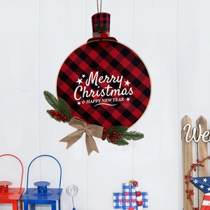 Christmas wreath with red black plaid pattern and pine needles hanging on white wooden wall